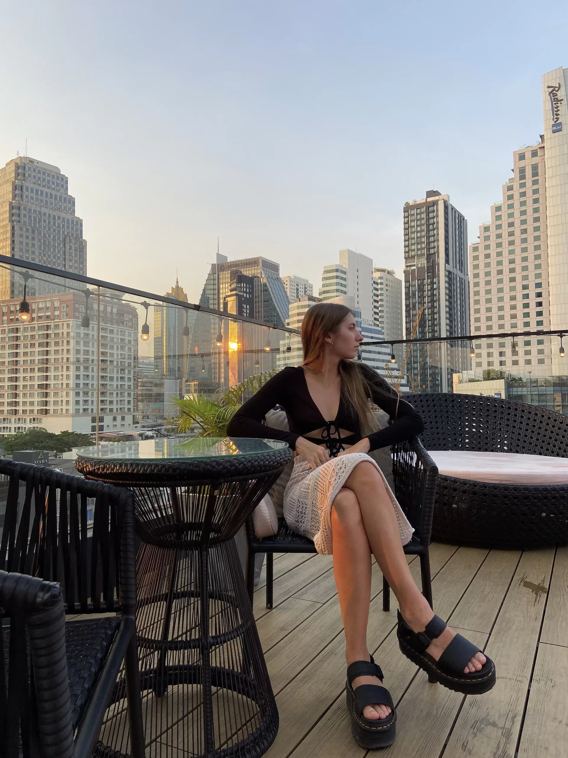 Girl on a Rooftop Bar in Bangkok, Thailand during sunset with skyscrapers
