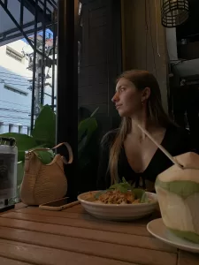 Girl in vegan restaurant with delicious Thai food and coconut water drink