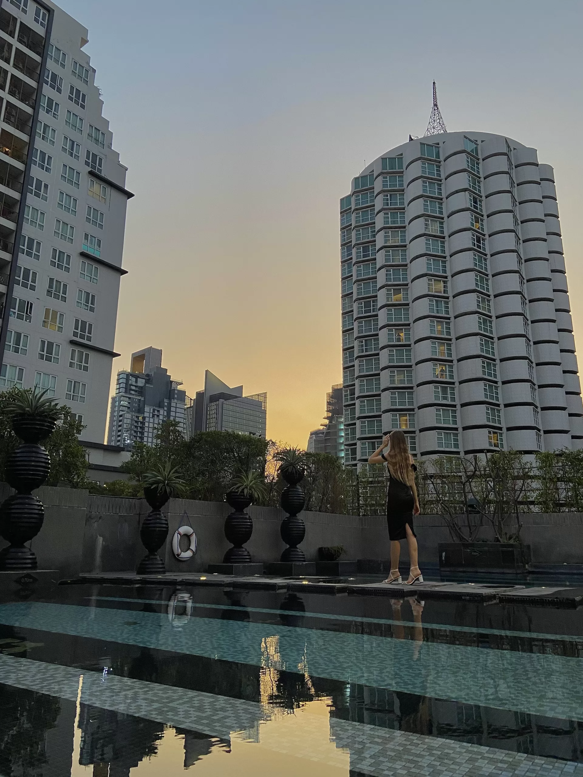 Aesthetic girl walking by a rooftop pool with skyscrapers in the background. Bangkok - Thailand.